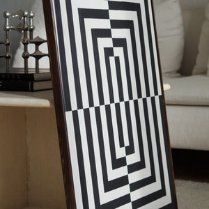 Pu&ograve; includere: Stampa d'arte astratta geometrica in bianco e nero in una cornice di legno scuro. La stampa presenta una serie di quadrati e rettangoli sovrapposti.