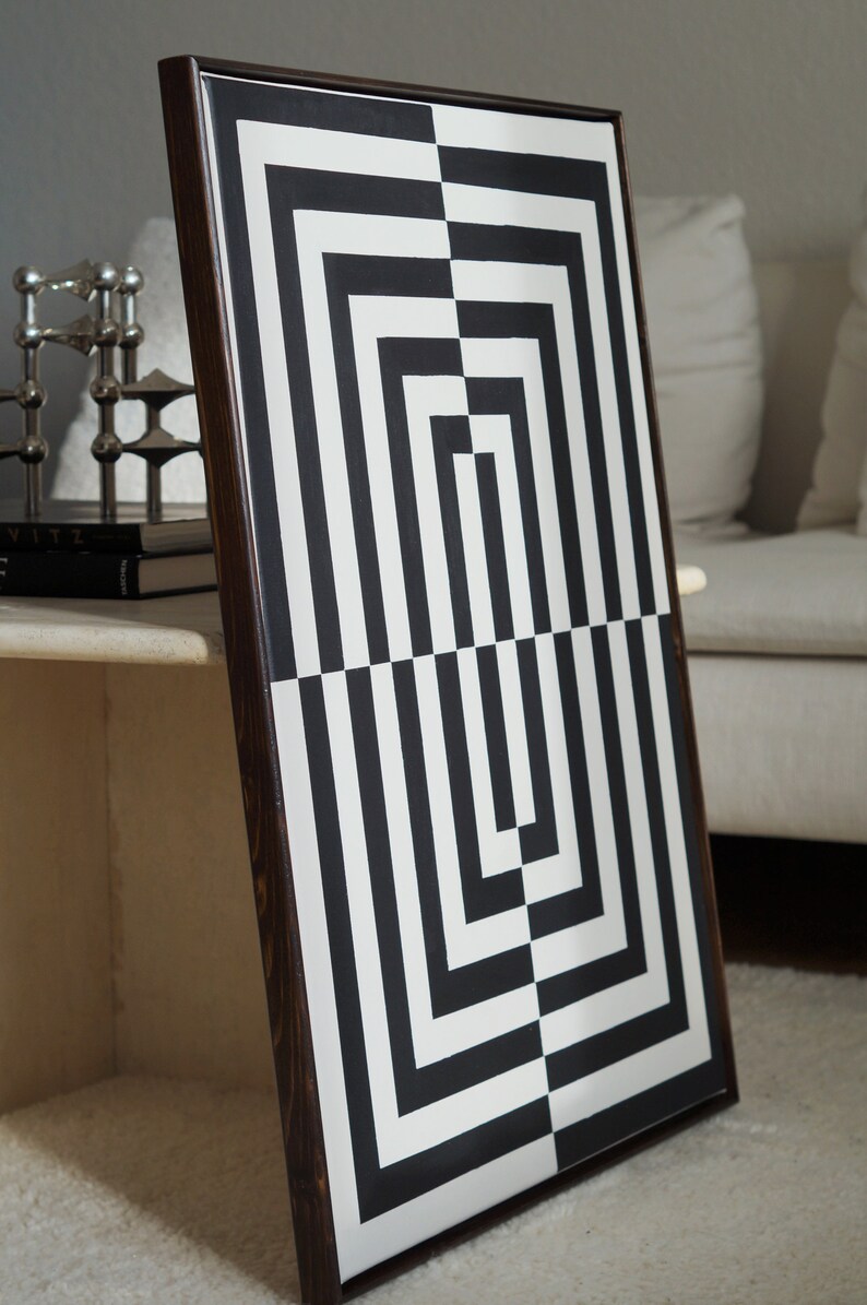 Pu&ograve; includere: Stampa d'arte astratta geometrica in bianco e nero in una cornice di legno scuro. La stampa presenta una serie di quadrati e rettangoli sovrapposti.