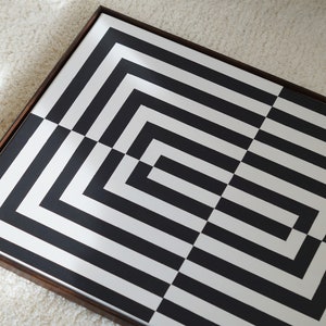Pu&ograve; includere: Motivo geometrico bianco e nero incorniciato in una cornice di legno scuro. Il motivo &egrave; composto da linee orizzontali e verticali che creano una serie di quadrati e rettangoli.
