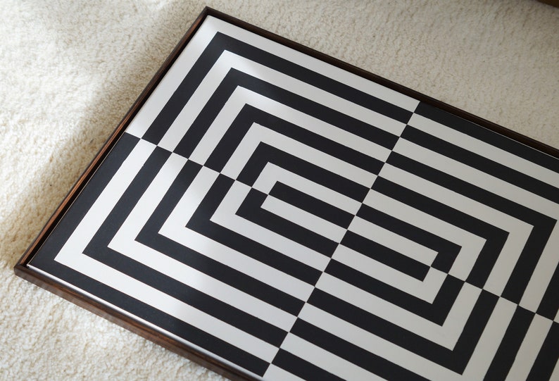 Pu&ograve; includere: Motivo geometrico bianco e nero incorniciato in una cornice di legno scuro. Il motivo &egrave; composto da linee orizzontali e verticali che creano una serie di quadrati e rettangoli.