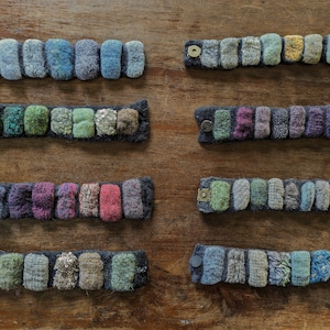 May include: Eight colorful felt bracelets with different patterns and colors. Each bracelet is made of small, individual felt pieces sewn together. The bracelets have a simple, minimalist design and are perfect for adding a touch of color to any outfit.