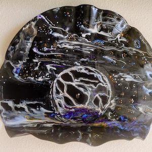 May include: A black vinyl record with a white, blue, and purple abstract design. The design resembles a galaxy with stars and swirling clouds.