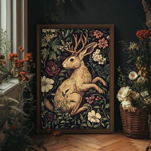 May include: A framed illustration of a brown rabbit with antlers sitting in a field of flowers. The rabbit is surrounded by green leaves and pink, white, and purple flowers. The background is a dark green.