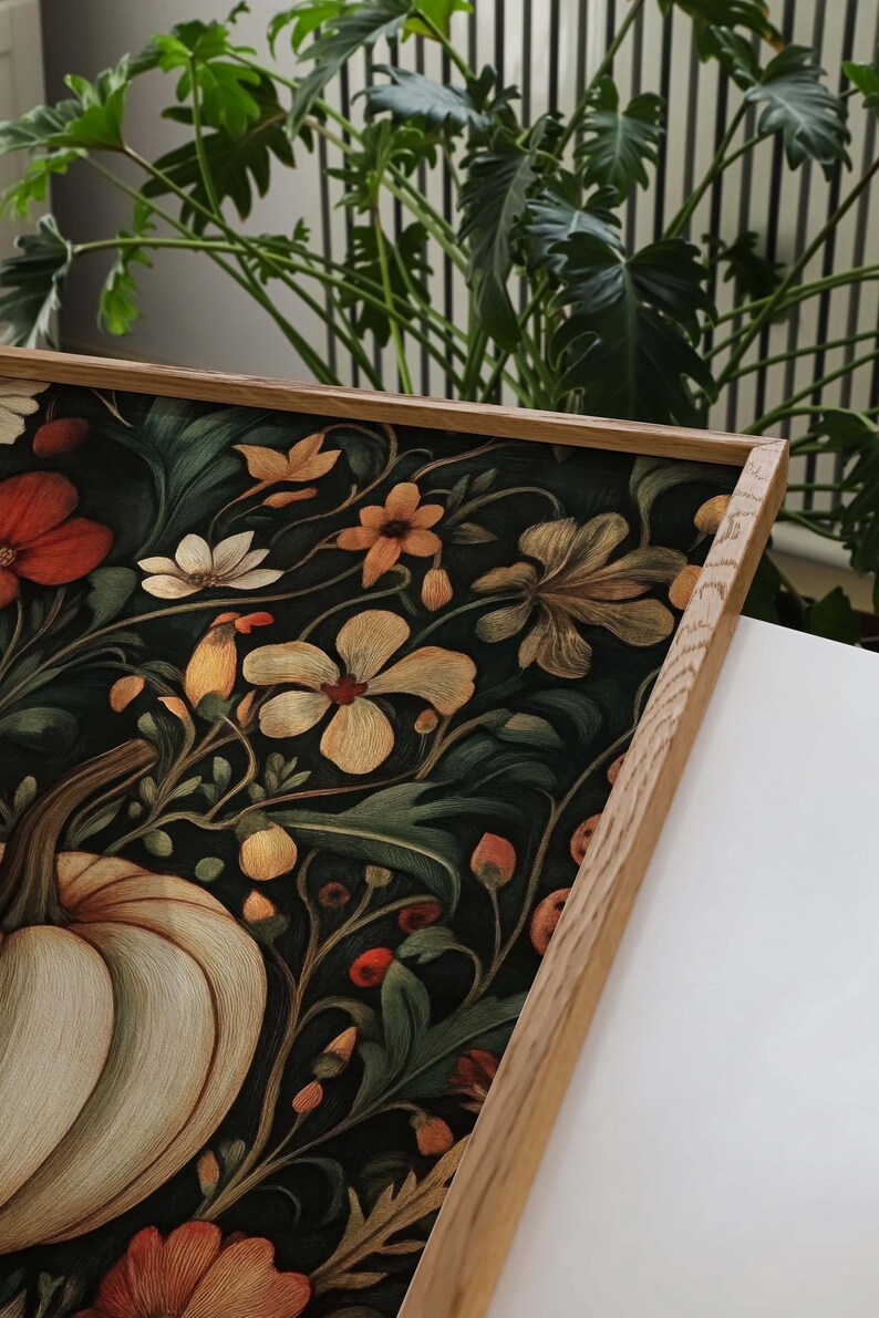 Peut inclure: Une impression d'art encadr&eacute;e avec un motif floral et de citrouille d&eacute;taill&eacute;. L'&oelig;uvre pr&eacute;sente une vari&eacute;t&eacute; de fleurs orange, blanches et jaunes, sur un fond vert fonc&eacute;. Le cadre est en bois clair.