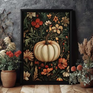 Peut inclure: Une impression d'art encadr&eacute;e repr&eacute;sentant une citrouille cr&egrave;me entour&eacute;e de fleurs orange, rouges et cr&egrave;me et de feuillage vert. L'&oelig;uvre d'art a un fond sombre et est encadr&eacute;e dans un cadre noir. Le th&egrave;me g&eacute;n&eacute;ral est l'automne et la r&eacute;colte.