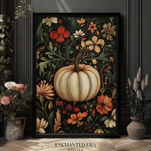 Peut inclure: Impression d'art encadr&eacute;e avec une citrouille cr&egrave;me entour&eacute;e de fleurs orange, rouges et jaunes et de feuilles vertes sur fond sombre. L'&oelig;uvre est dans un cadre noir et porte le texte "ENCHANTED ERA ATELIER" en bas.