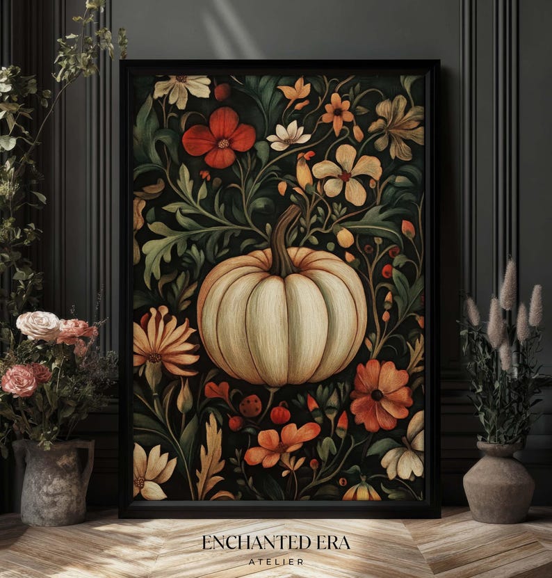 Peut inclure: Impression d'art encadr&eacute;e avec une citrouille cr&egrave;me entour&eacute;e de fleurs orange, rouges et jaunes et de feuilles vertes sur fond sombre. L'&oelig;uvre est dans un cadre noir et porte le texte "ENCHANTED ERA ATELIER" en bas.