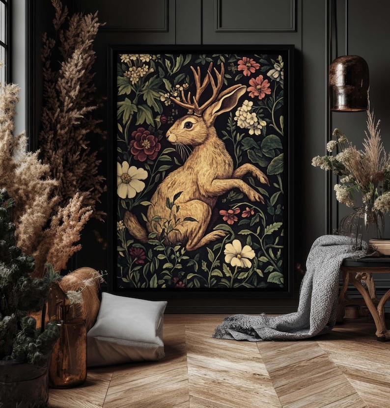 May include: A vintage-style illustration of a brown rabbit with antlers, surrounded by colorful flowers and foliage. The artwork is framed and displayed on a dark wall.