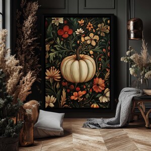 Peut inclure: Une impression d'art encadr&eacute;e repr&eacute;sentant une citrouille cr&egrave;me entour&eacute;e de fleurs orange, blanches et jaunes et de feuillage vert sur un fond sombre. L'&oelig;uvre, dans un cadre noir, est id&eacute;ale pour la d&eacute;coration d'automne.