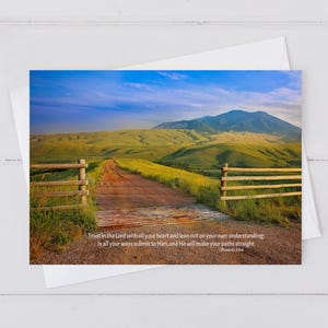 May include: A greeting card featuring a scenic landscape with a dirt road, wooden fence, and a mountain in the background. The card includes the text "Trust in the Lord with all your heart..." from Proverbs 3:5-6.