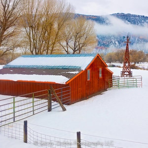 Rustic red barn in snowy winter landscape, with autumn trees in background. Available in prints or canvases.