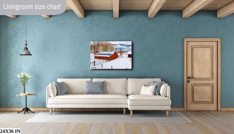 May include: A white couch with pillows sits in front of a blue wall with a framed photograph of a red barn in a snowy landscape. The text "24X36 IN" is visible in the bottom left corner of the image.