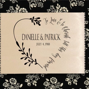 May include: A beige satin ribbon with a black heart design and the text "To Love & To Cherish Till This Day Forward" and "Danielle & Patrick" with the date "July 4, 1988".