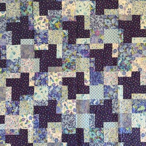 May include: A quilt featuring a repeating pinwheel pattern composed of dark purple fabric squares with a subtle swirling stitch design, interspersed with various light blue, white, and lavender floral and geometric patterned fabric squares.