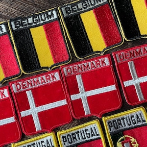 May include: Embroidered patches featuring the flags of Belgium, Denmark, and Portugal. The Belgium patches display black, yellow, and red vertical stripes. The Denmark patches have a white cross on a red background. The Portugal patches show green and red designs.