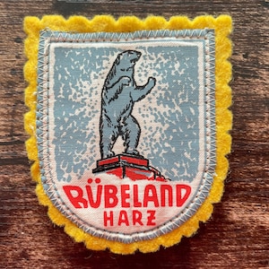 May include: A handmade wooden sign with the text "Welcome" in a handwritten style. The sign is painted white with a distressed finish and features a decorative floral design in shades of pink and green. It is designed for indoor or outdoor use.