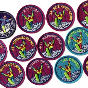 May include: A collection of eleven circular embroidered patches featuring skiers in yellow jackets and green skis on snowy slopes. Each patch displays a unique French ski resort name in yellow text, including Avoriaz, Le Corbier, and Val d'Isere.