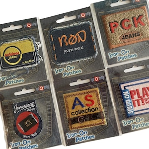 May include: A selection of iron-on patches, each packaged on a card printed with a denim design. The patches display text such as "outdoor jeans," "BON jeans wear," and "PCK JEANS," in diverse colours and fonts.