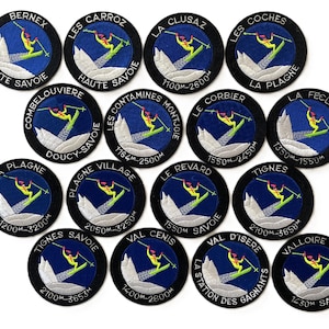 May include: A collection of circular patches with a black border and a blue centre. Each patch features a skier, mountain graphic, and text indicating a ski resort location and elevation range in metres.