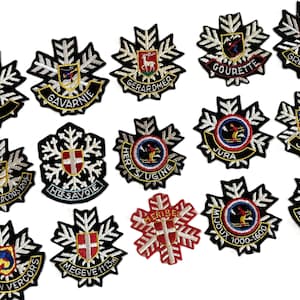 Może przedstawiać: Kolekcja haftowanych naszywek z czarnym wzorem płatka śniegu. Każda naszywka zawiera inny emblemat, tekst i schemat kolorów, w tym nazwy różnych miejsc, takich jak "GAP" i "JURA".