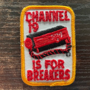 Pode incluir: Patch bordado com fundo branco, borda amarela e o texto "CHANNEL 19 IS FOR BREAKERS" em vermelho. O patch apresenta um design vermelho e preto de um rádio CB.
