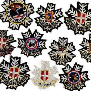 Puede incluir: Un conjunto de parches bordados con varios diseños. Los parches presentan bordes negros y blancos en forma de copo de nieve, con diseños centrales coloridos que incluyen escudos, esquiadores y texto como "MORZINE-AVORIAZ" y "VALTHORENS 2300-3300".