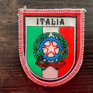 Peut inclure: Un écusson brodé en forme de bouclier aux couleurs du drapeau italien vert, blanc et rouge. Le texte ITALIA est imprimé en haut. Le centre affiche l'emblème de l'Italie avec une roue dentée bleue, une étoile blanche et un ruban rouge.