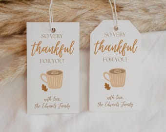 Puede incluir: Dos etiquetas de regalo rectangulares de papel blanco con cordeles blancos. Cada etiqueta presenta el texto SO VERY thankful FOR YOU! en marrón, un gráfico de una taza de café color canela, una pequeña hoja marrón y el texto with love, the Edwards Family.