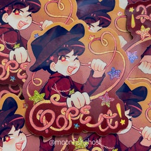 May include: A sticker featuring a cartoon character in a burgundy outfit and hat, holding a rope with stars. The word "Dope!" is written in a stylized font. The sticker has a glittery finish and the artist's handle, @moonfishghost, is at the bottom.