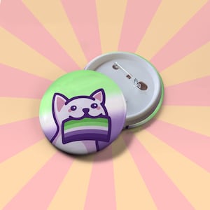 May include: A white cat with a green, white, and purple flag in its mouth. The cat is smiling and has a pink nose. The flag is a symbol of the genderqueer community. The button is 1.25 inches in diameter.