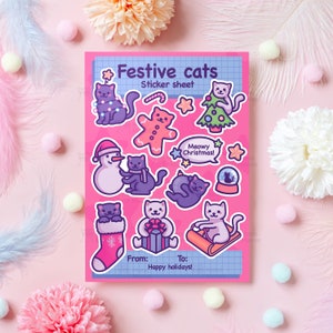May include: A sheet of festive cat stickers on a pink background. The stickers feature various cats in holiday themes, including a snowman, Christmas tree, and gift. Text on the sheet reads "Festive cats" and "Meowy Christmas!"