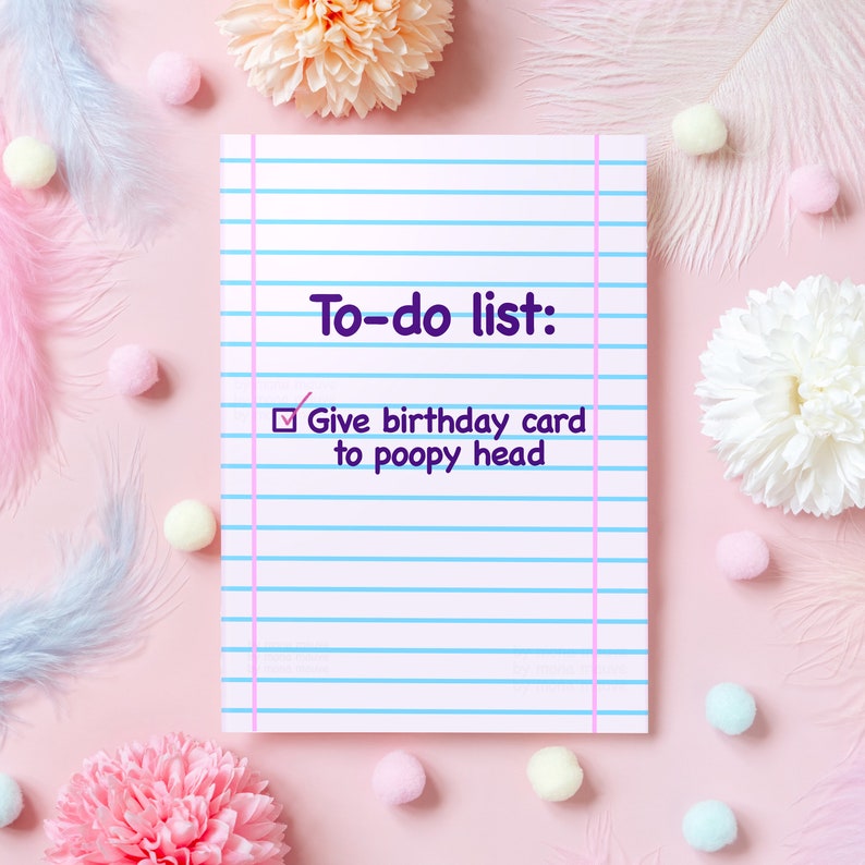 K&ouml;nnte beinhalten: Ein Notizblock mit rosa Hintergrund, mit dem Text "To-do list: Give birthday card to poopy head." Der Notizblock hat blaue Linien und einen rosa Rand. Dekorative Blumen, Federn und Pompons umgeben den Notizblock.