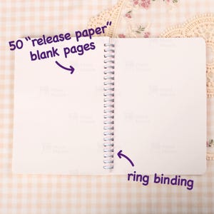 May include: Open notebook with 50 blank pages and ring binding. Text on the image reads "50 release paper blank pages" and "ring binding". The pages are white.