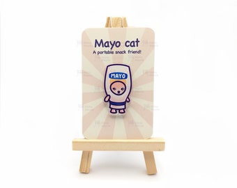 May include: A white card with pink stripes and the text "Mayo cat" and "A portable snack friend!"  A cartoon cat wearing a mayonnaise jar costume is on the card. The card is on a small wooden easel.