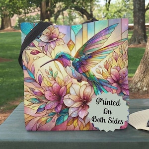 May include: A tote bag with a colorful hummingbird and floral design. The bag is printed on both sides. "Printed On Both Sides" is written on a white circle sticker.