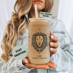 May include: A brown reusable tumbler with a bamboo lid and a black and white graphic of a lion with the text "Leo July 23 - August 22" and "ALL ZODIAC SIGNS".