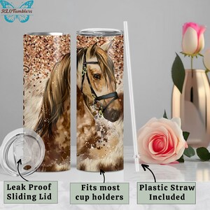 May include: A stainless steel tumbler with a brown and white horse illustration. The tumbler has a clear sliding lid and a matching straw. The tumbler is on a white background with a pink rose.