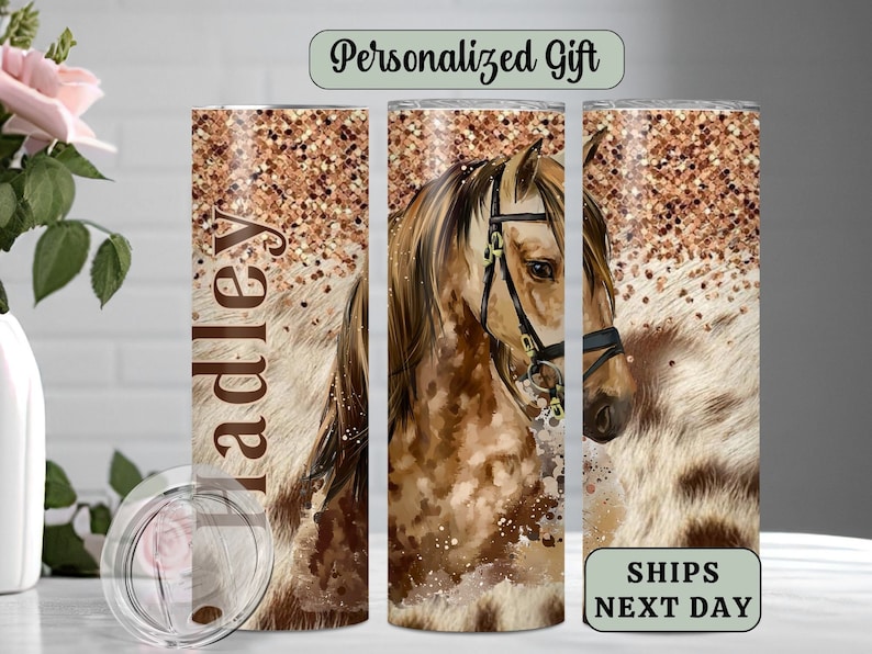 May include: Personalized stainless steel tumbler with a brown and white horse illustration and gold glitter background. The tumbler has the name "Hadley" printed on it.