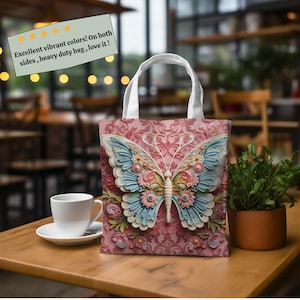 K&ouml;nnte beinhalten: Eine rosa Tragetasche mit einem Schmetterlingsdesign. Der Schmetterling hat blaue und wei&szlig;e Fl&uuml;gel mit floralen Akzenten. Die Tasche hat wei&szlig;e Griffe und den Text "Excellent vibrant colors! On both sides, heavy duty bag, love it!"
