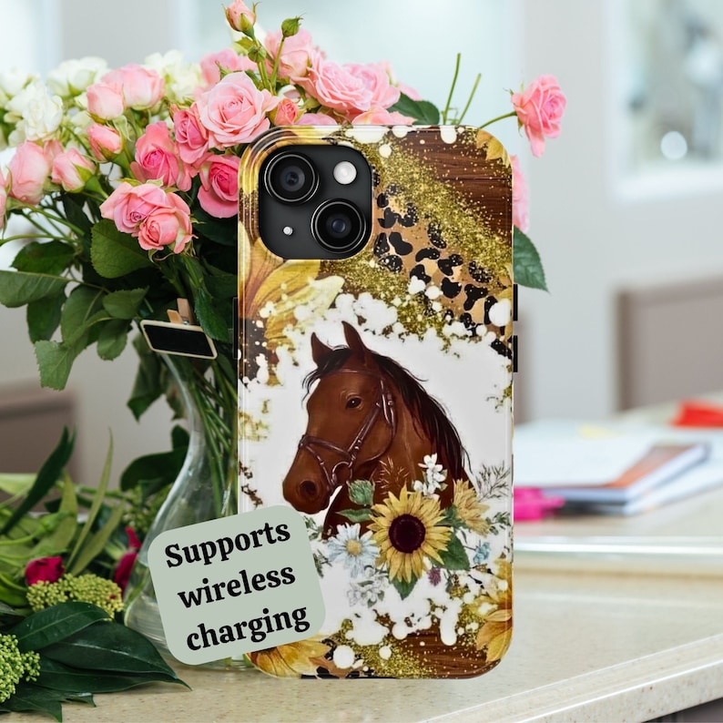 May include: A brown horse with a sunflower and white flowers on a gold glitter and leopard print phone case. The case supports wireless charging.