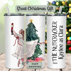 May include: Three white tumblers with different designs. The first tumbler features a watercolor illustration of a young girl in a white dress dancing with a nutcracker. The second tumbler features a watercolor illustration of a Christmas tree with a young girl in a white dress dancing in front of it. The third tumbler has the text "THE NUTCRACKER Kaylee as Clara 2024".