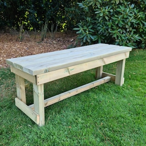 May include: A wooden bench with a natural finish, made of untreated wood. The bench is sitting on a grassy lawn.