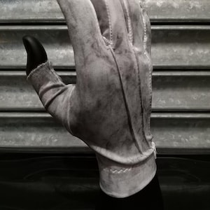 May include: A white cotton glove with a textured surface. The glove is worn and has a faded appearance.