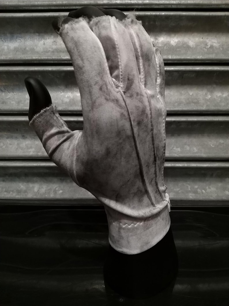 May include: A white cotton glove with a textured surface. The glove is worn and has a faded appearance.