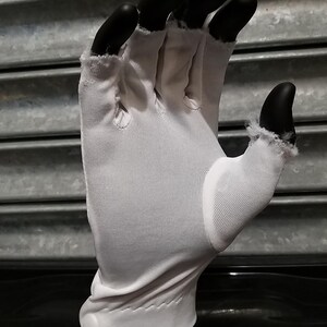 May include: White cotton gloves with a button closure on the wrist. The gloves are made of a thin, breathable fabric and are designed to protect hands from dirt and grime.