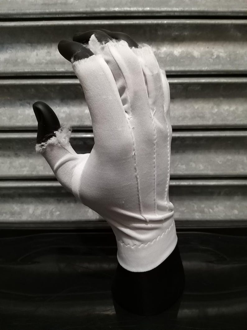 May include: A white cotton glove with a seam down the middle of each finger. The glove is on a black mannequin hand.