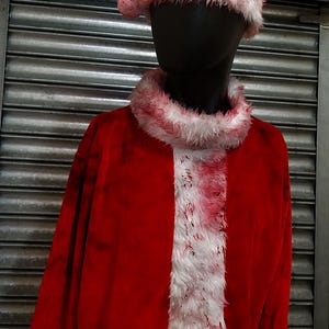 Peut inclure: Un costume de Père Noël rouge et blanc avec une bordure en fourrure blanche et des éclaboussures de sang. Le costume est porté par un mannequin au visage noir.