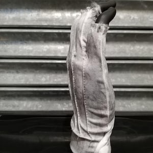 May include: A white cotton glove with a frayed edge and a button closure. The glove is worn and has a distressed look.