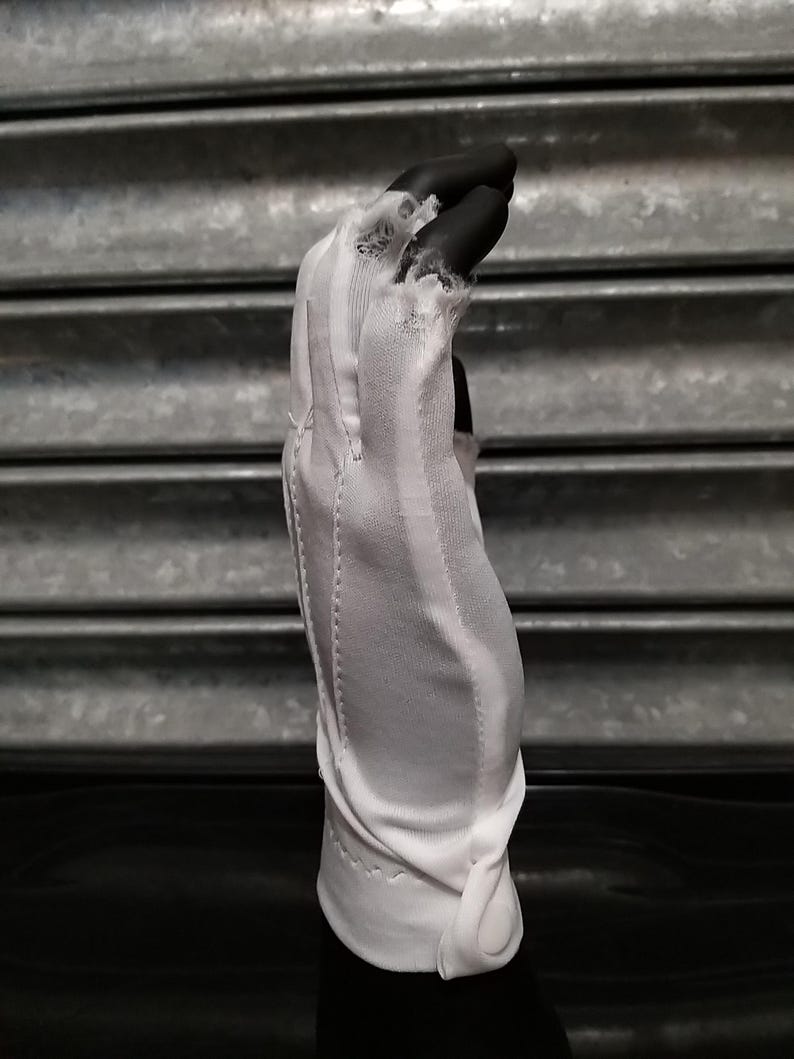 May include: White cotton driving gloves with a button closure. The gloves are made of a thin, breathable fabric and have a ribbed texture.
