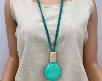Lightweight crackled aqua pendant with wood accent. Faux suede cord